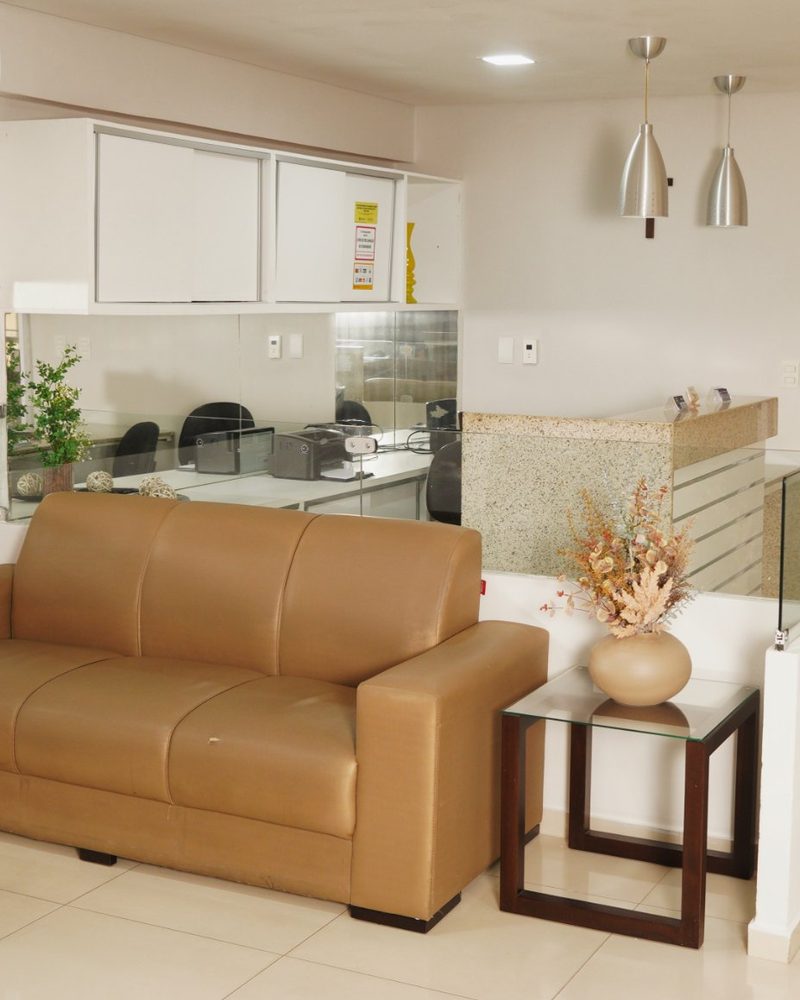 Sala de espera com sofá de couro e arranjo de flores secas
