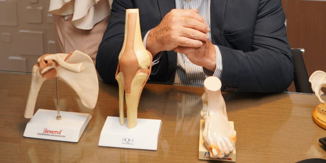 Mesa do consultório de ortopedia com modelos anatômicos de ombro, joelho e pé